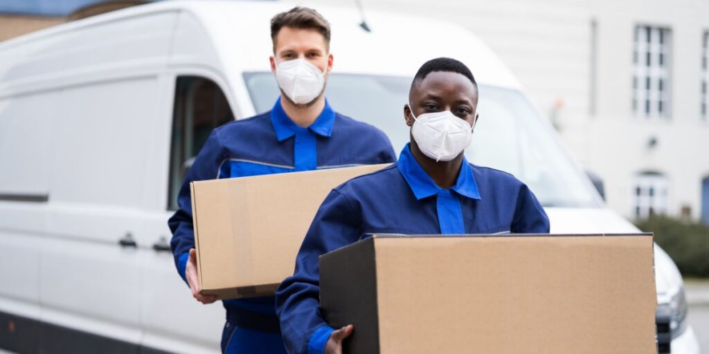 2 man moving boxes with mask on