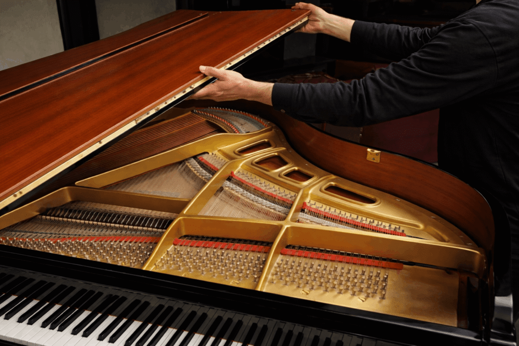 person removing the top lid of the grand piano